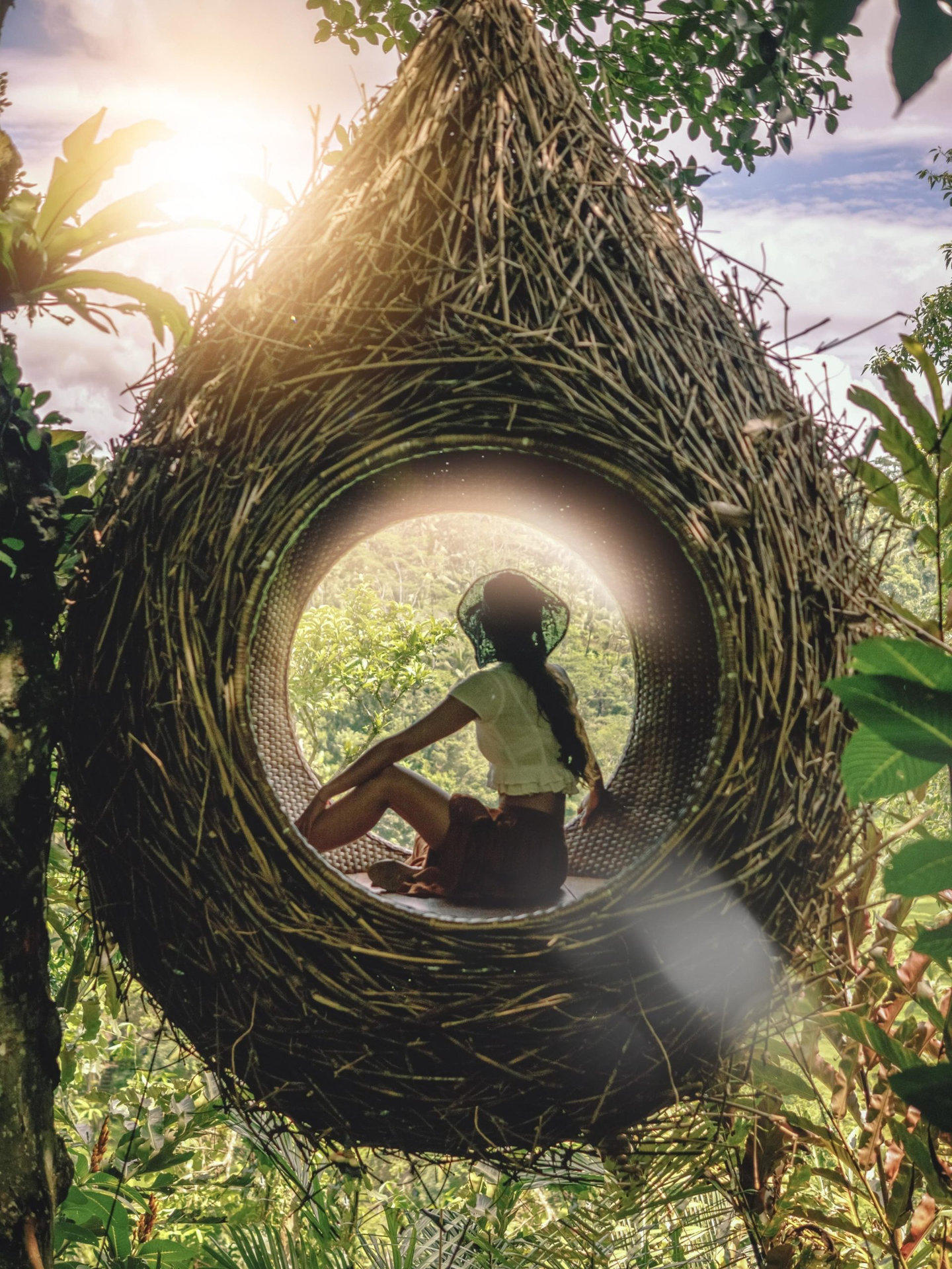 The girl in a giant nest looks at the jungle. Ecology, eco housing, harmony