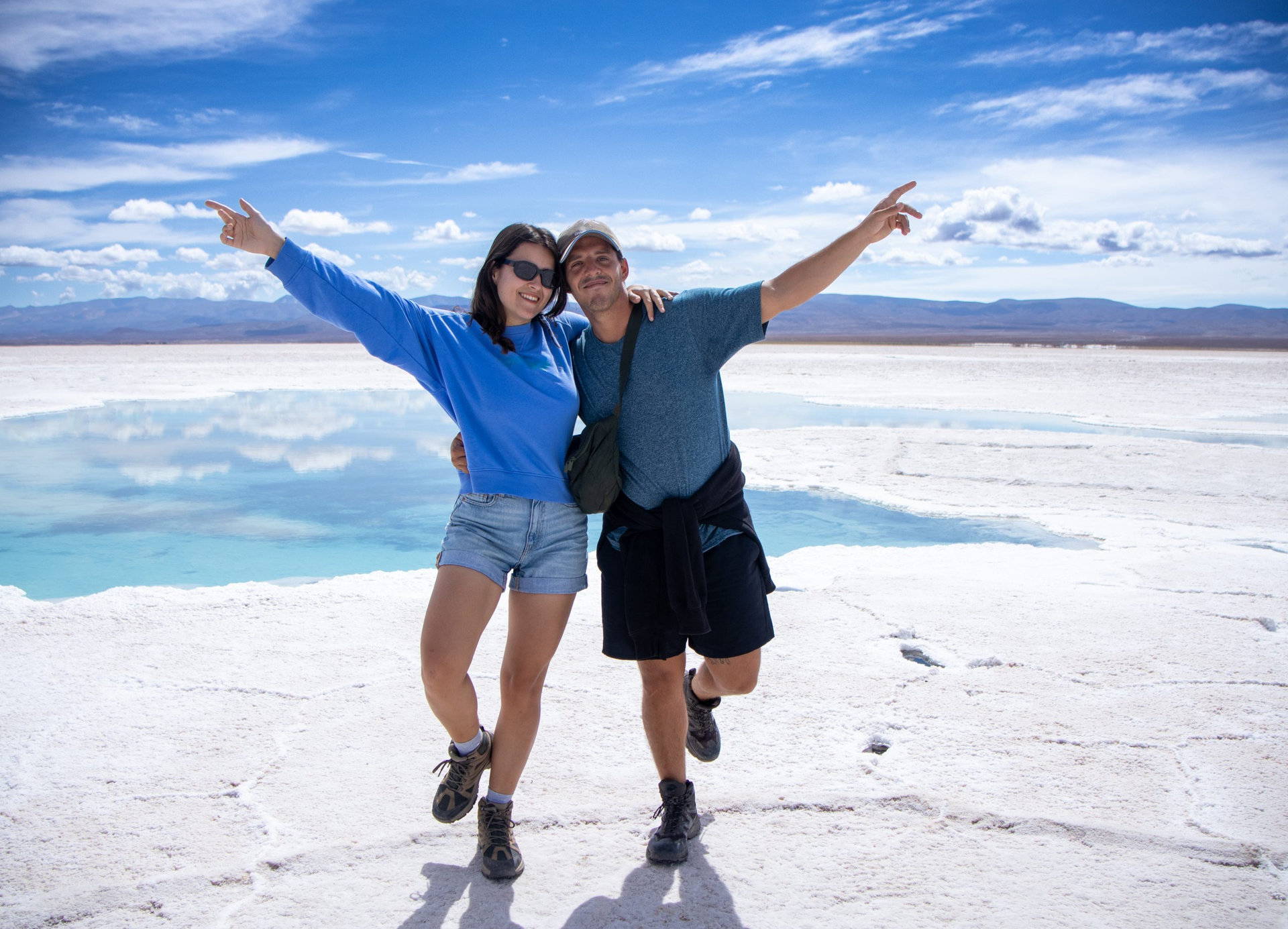 Happy young man and woman couple in a fun attitude posing in the spectacular Salinas Grandes of Argentina enjoying their trip to South America.