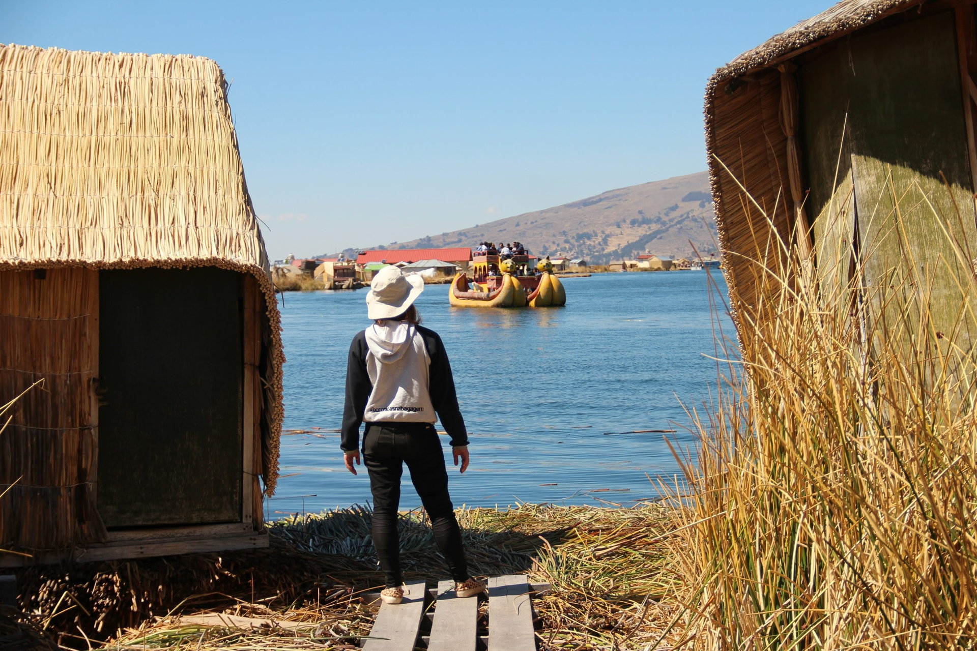 mulher observando barco de totora no lago titicaca em puno, peru
