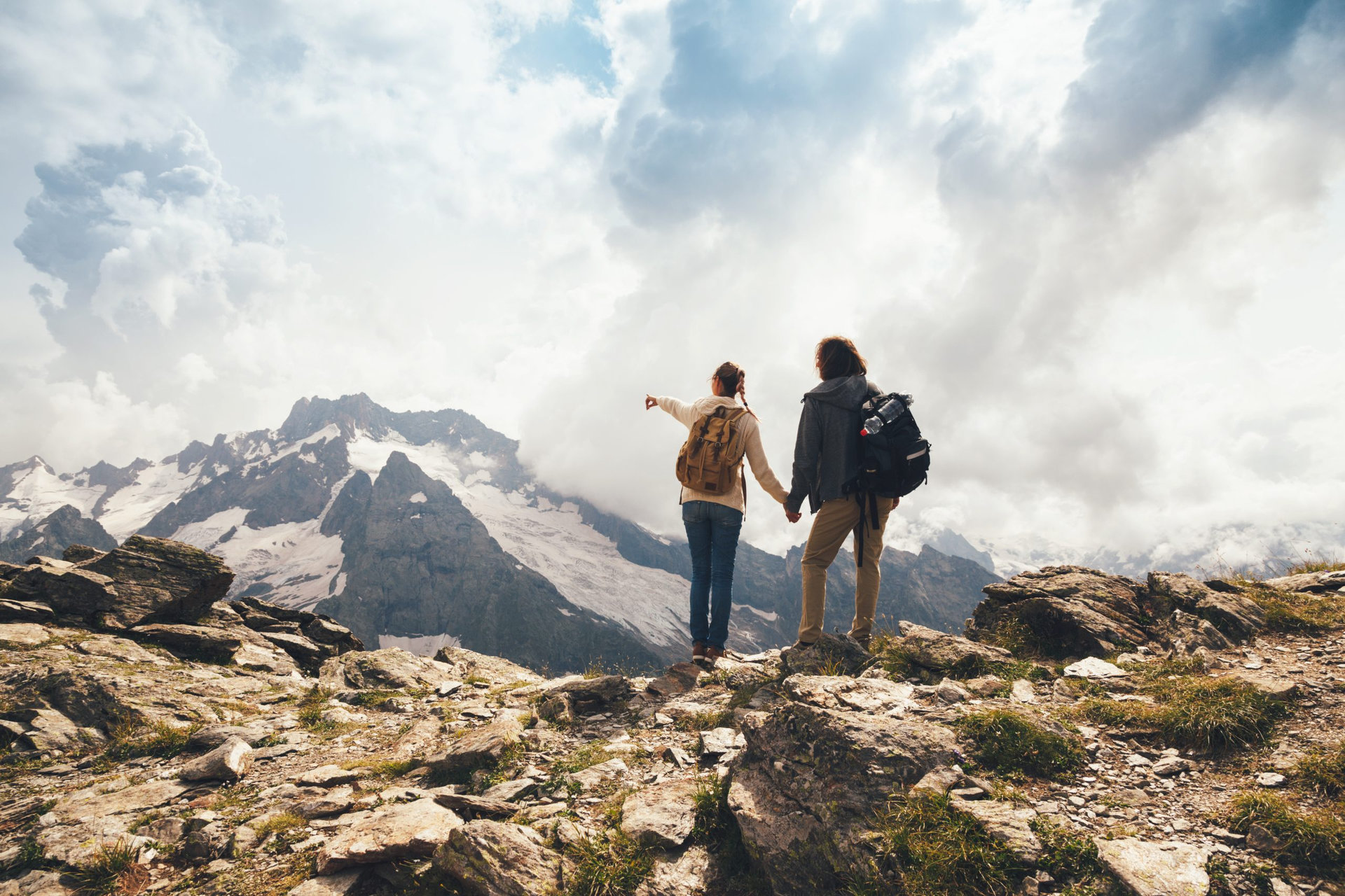 Man and woman standing and hugging on the top of the mountain, autumn hike with backpacks, alpine view