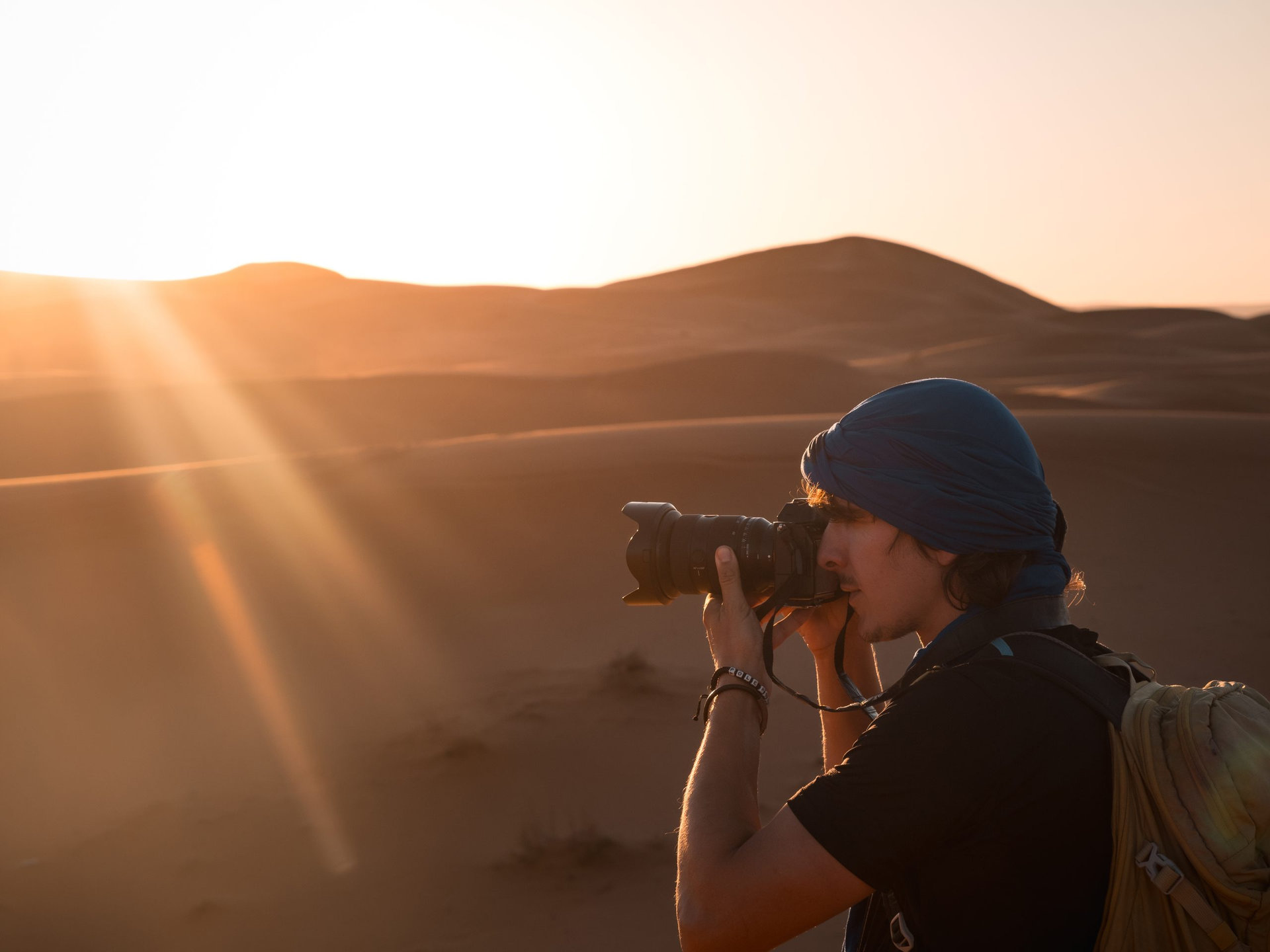 Photographer taking photos of sunset over sand dunes in merzouga desert, morocco