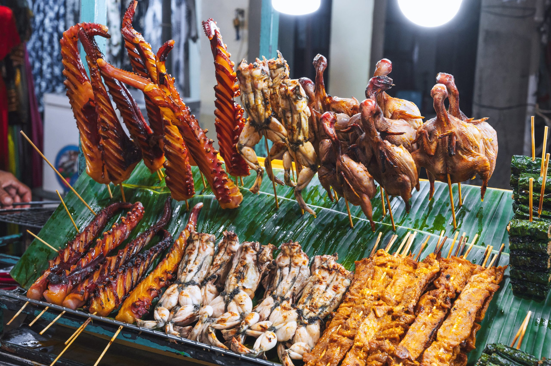 Grilled octopus and meat skewers sold as snacks from a street vendor in Hoi An night market.