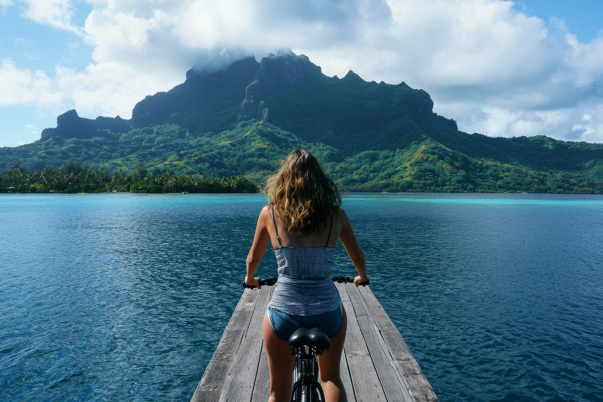 In French Polynesia, a girl has fun biking on an electric bicycle rental during her summer vacation on the island of Bora Bora, a popular Tahiti travel destination