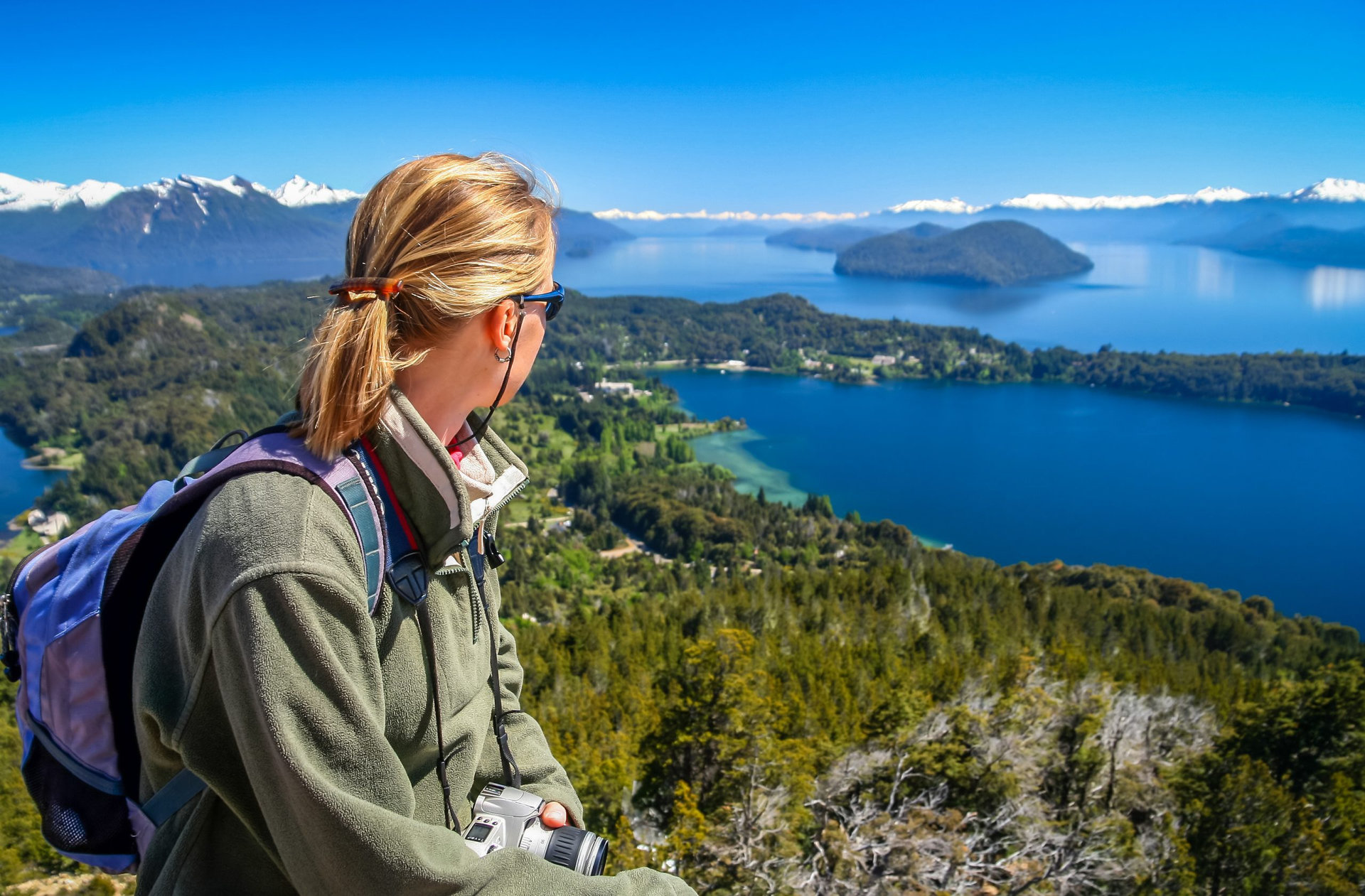 Woman sitting on the viewpoint on top of mount Cerro Campanario, Argentina and admiring the stunning views of Lake District