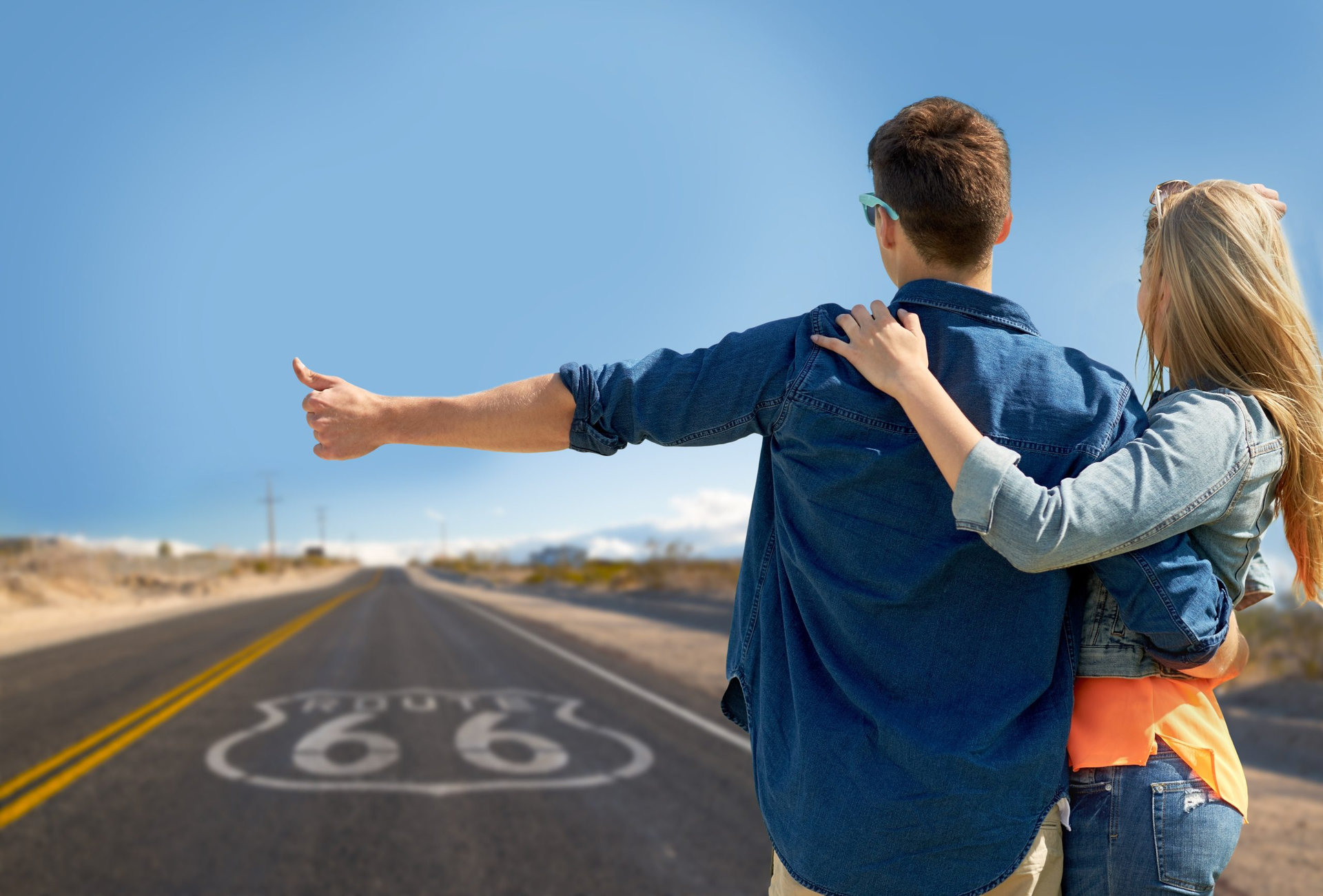 road trip, hitchhike, travel and gesture concept - happy couple hitchhiking over us route 66 background