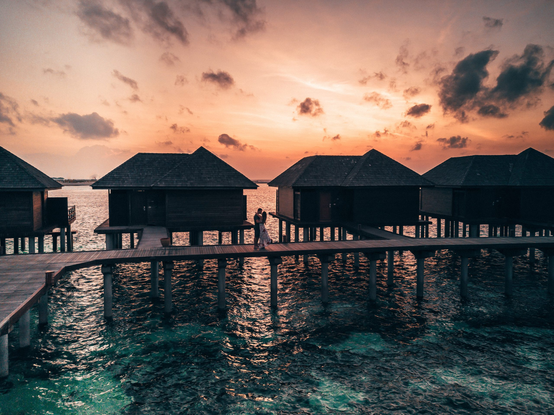 Aerial drone photo - A couple embraces during a sunrise in the Maldives