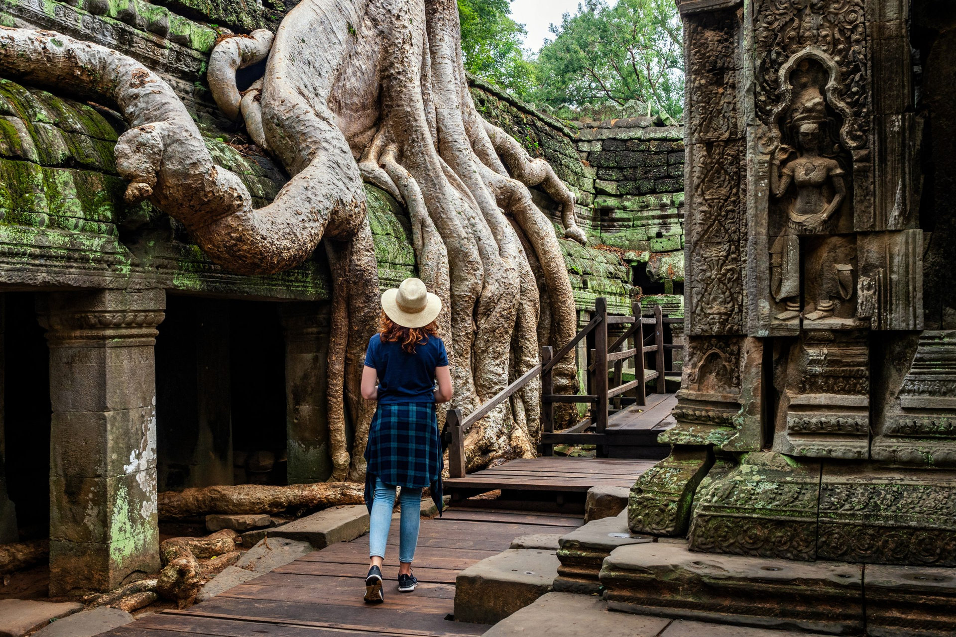 Traveler exploring ancient ruins of Ta Prohm temple at Angkor, Siem Reap, Cambodia.
