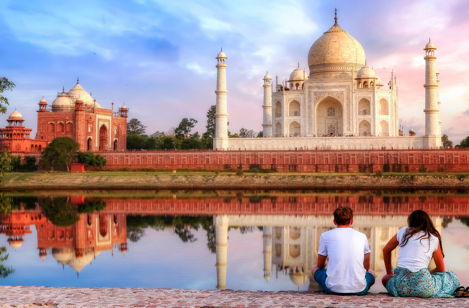 Taj Mahal sunset view from Mehtab Bagh on the banks of river Yamuna with a tourist couple enjoying a romantic moment.