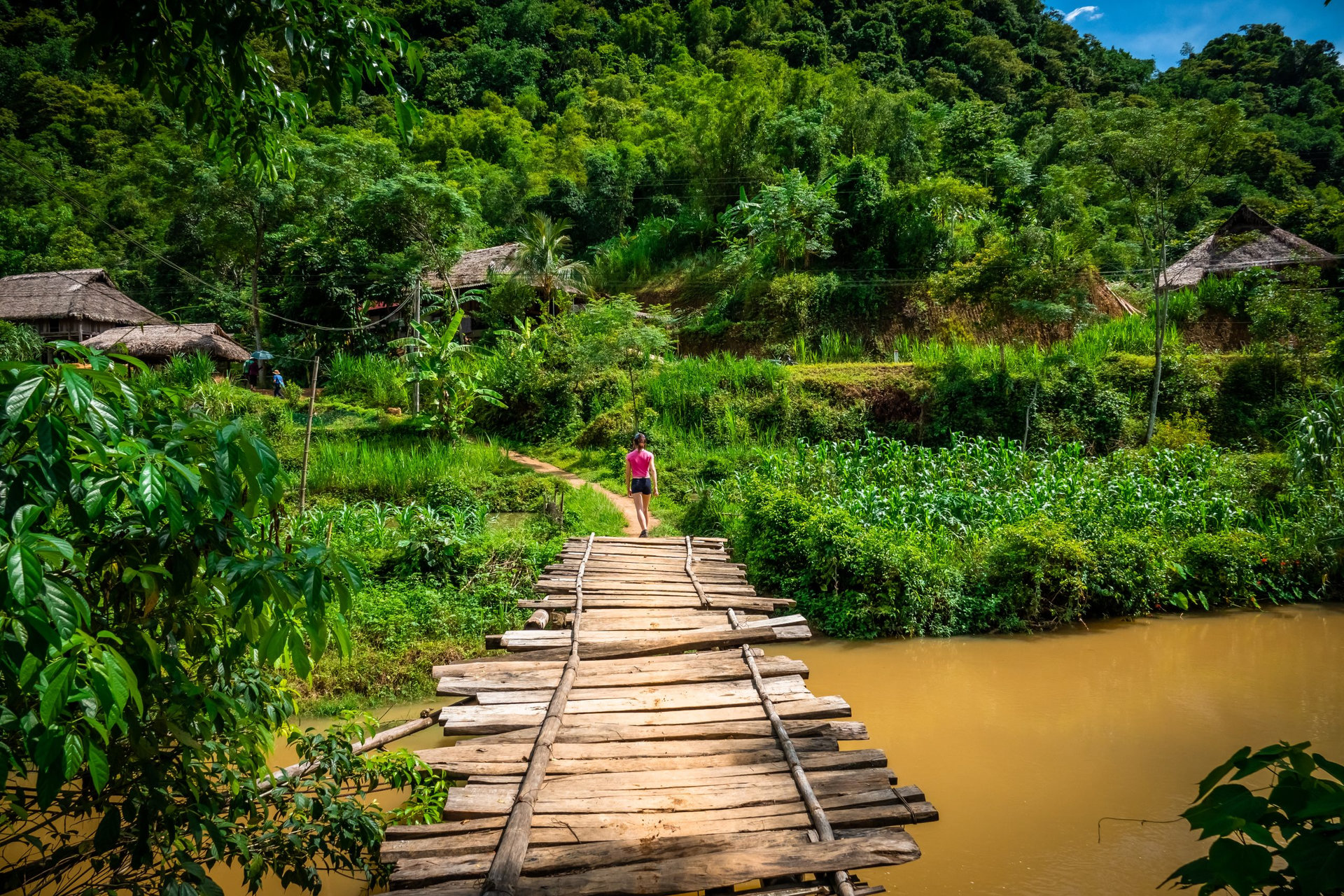 young woman hiking on a wooden bridge in Pu Luong, rural area close to Mai Chau, Vietnam.