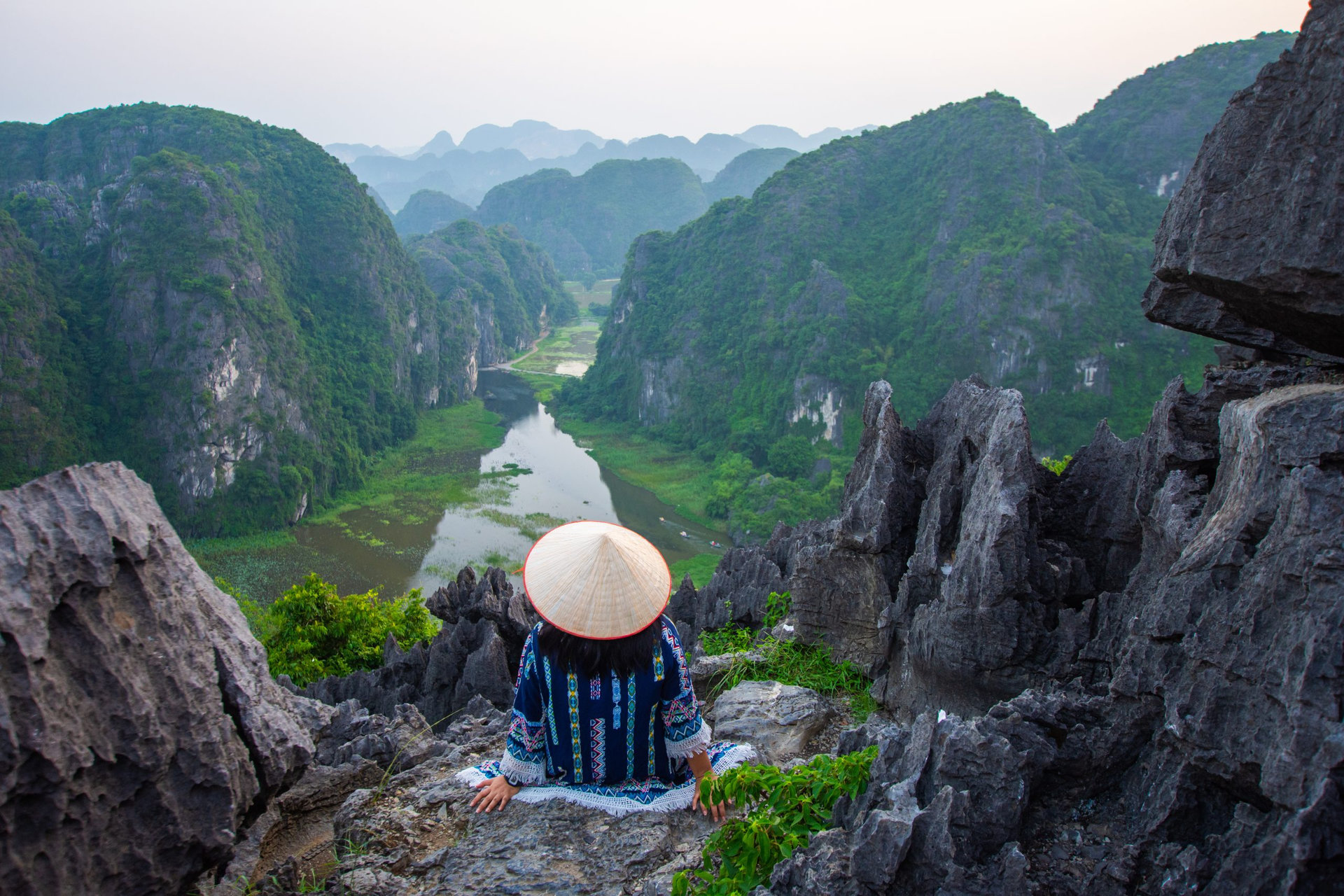 happy woman sitting on peak of mountain at Mua Cave, Ninh Binh, Vietnam at evening, subject is blurred, low key and noise.