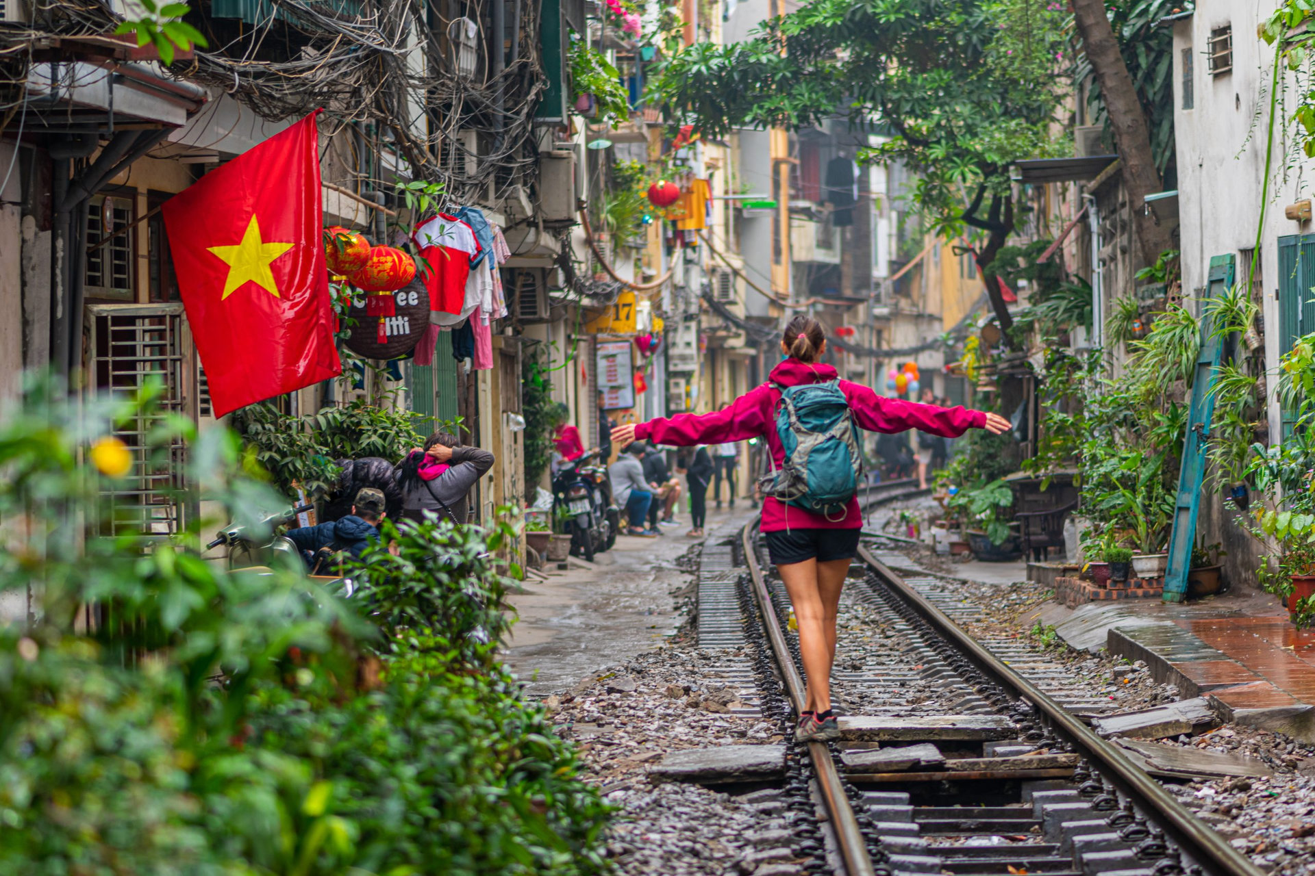 Traveler tourist with backpack trying to keep balance on train rail in Hanoi, Vietnam. The Hanoi Old Quarter is a popular tourist attraction.