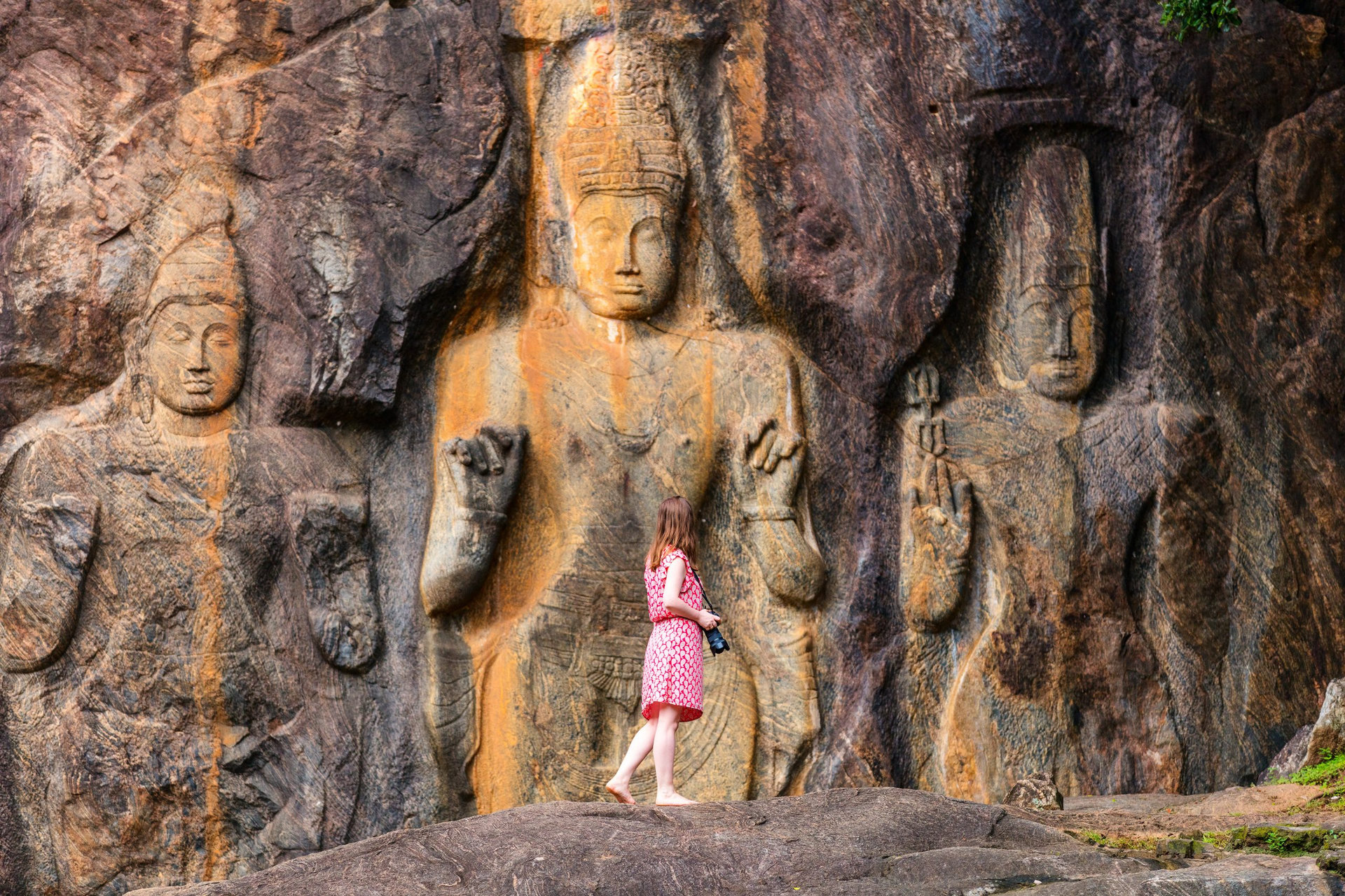 Female tourist visiting Buduruwagala temple with well preserved carvings on the wall in Wellawaya Sri Lanka