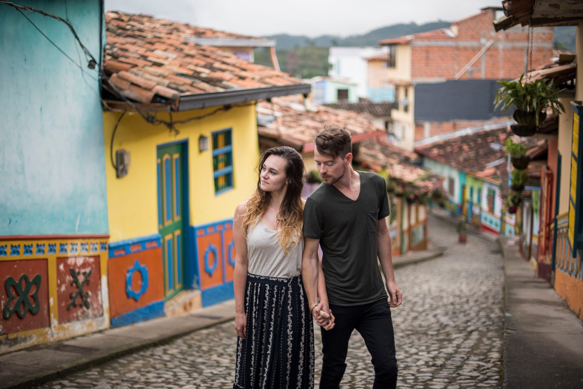 travel couple hiking through old town guatape in colombia