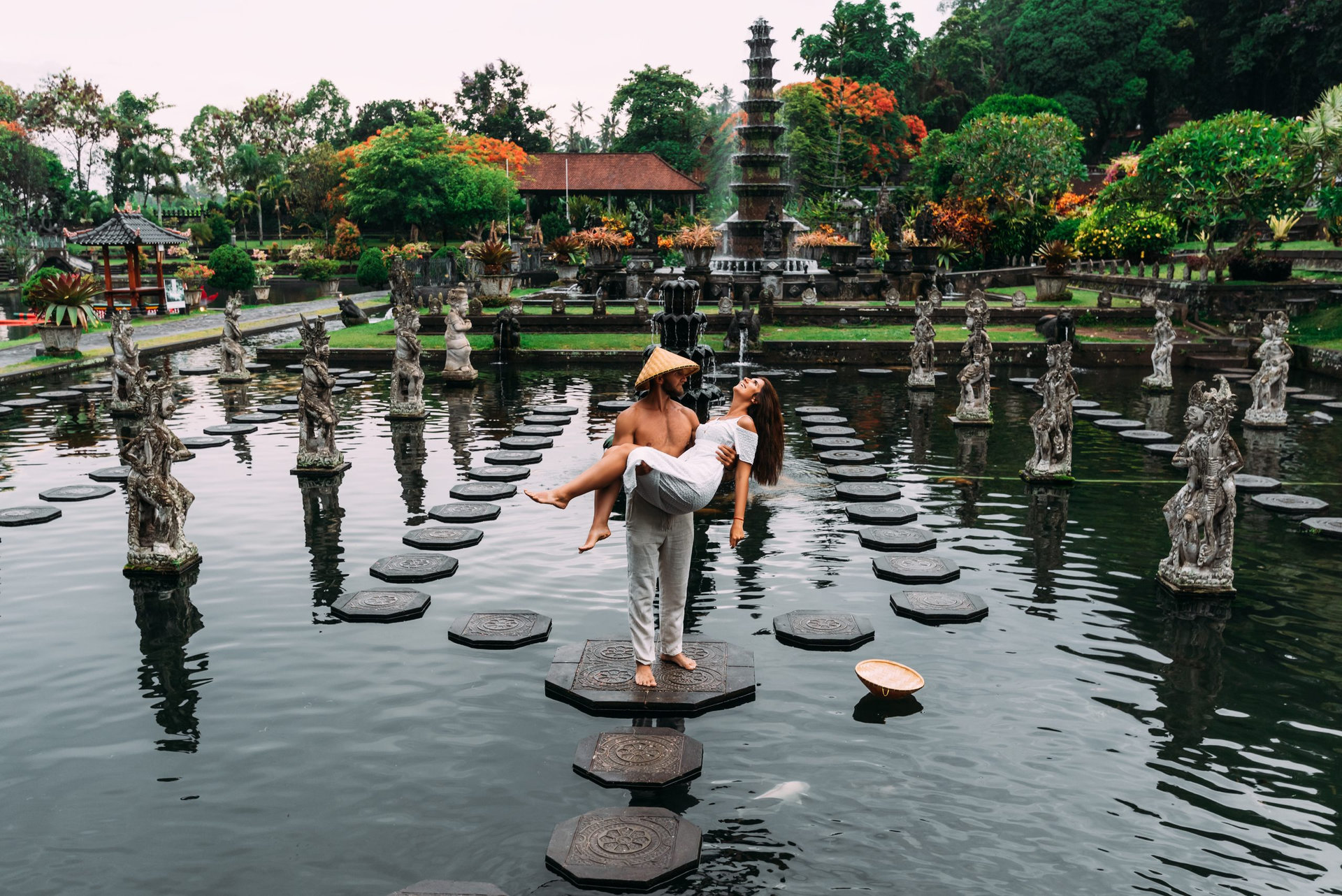 A beautiful couple is traveling on the island of Bali in Indonesia. A couple walks through a water temple in Indonesia. Travel to Asia. The tourists travel. The man lifted the woman in his arms