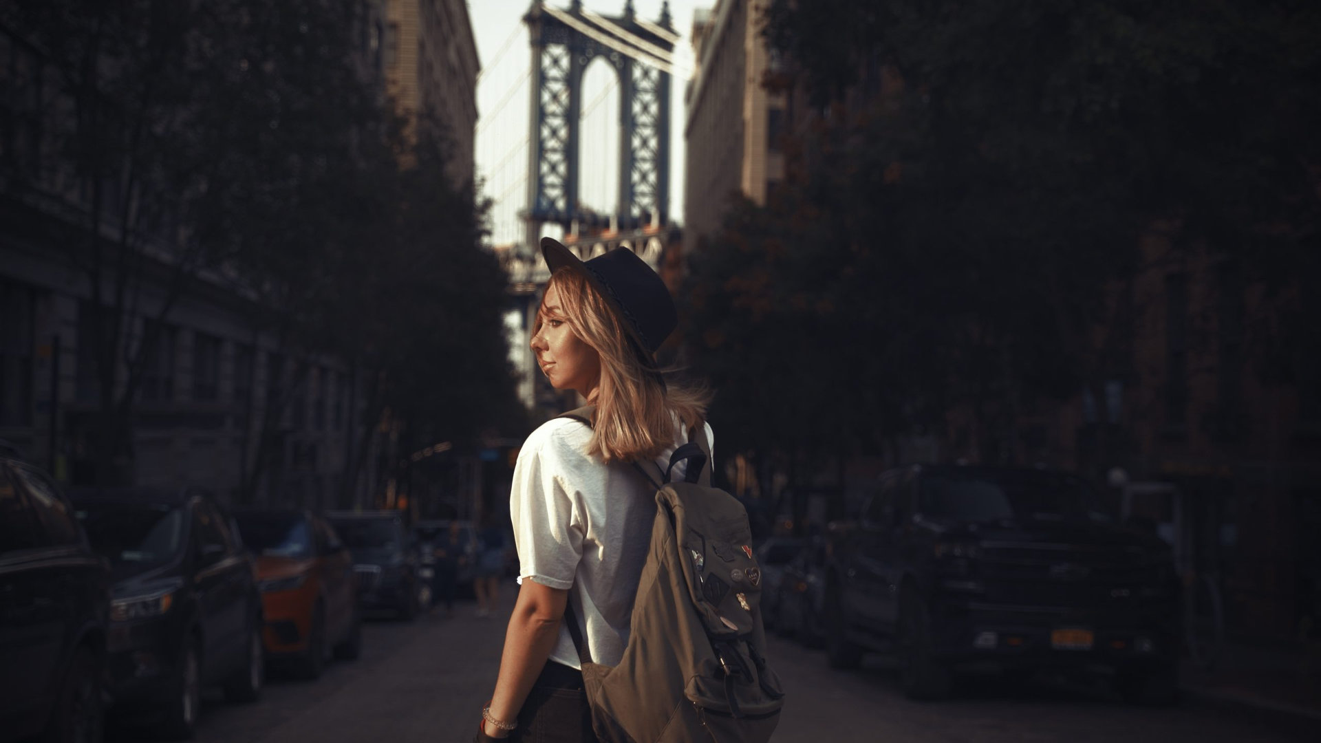Fashion video of pretty woman near the Brooklyn Bridge in New York City at Sunrise. Young traveling woman in a hat enjoying American holidays.