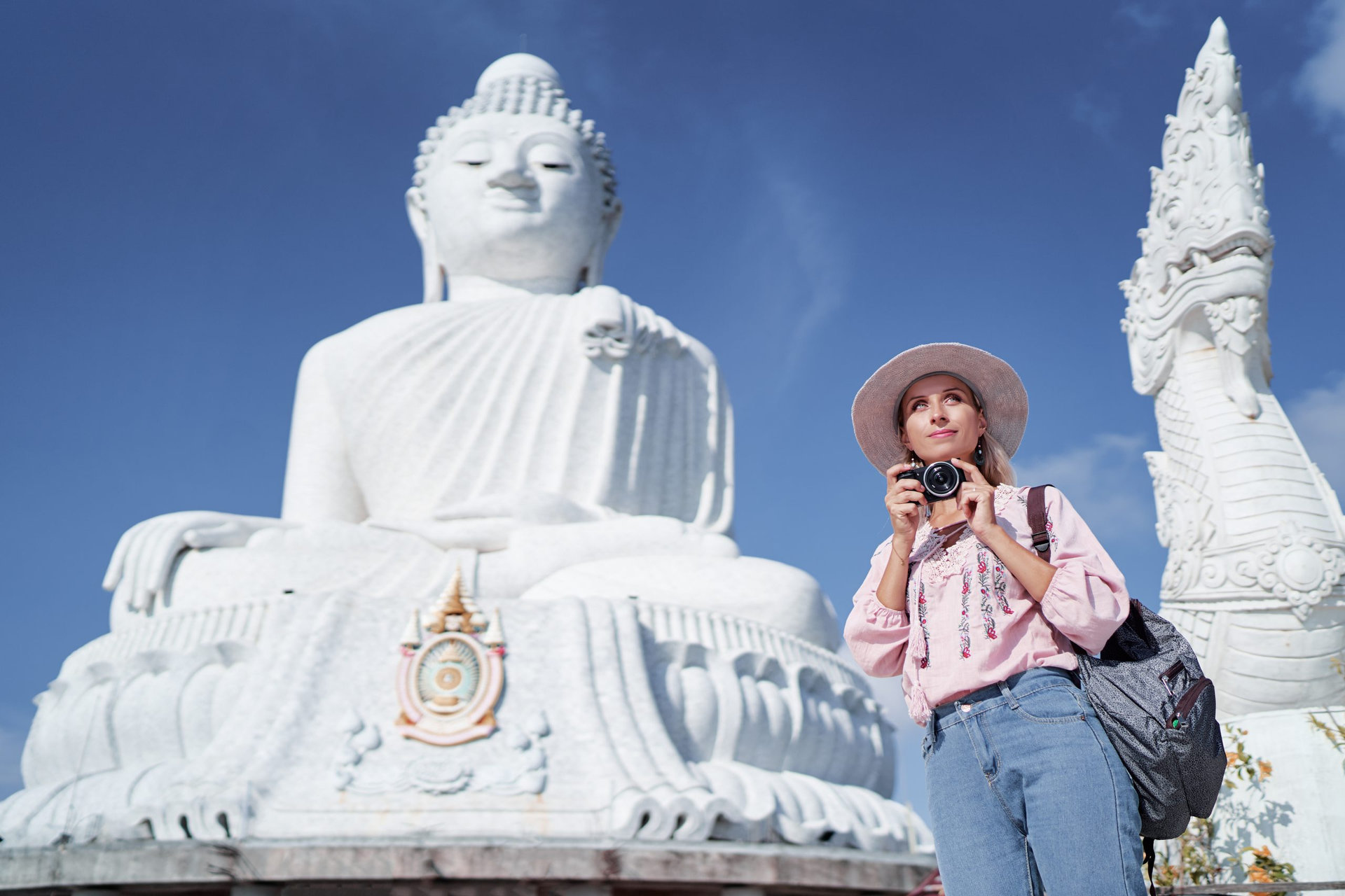 Traveling by Thailand. Pretty young woman taking photo in the Big Buddha Temple, famous Phuket sightseeing.
