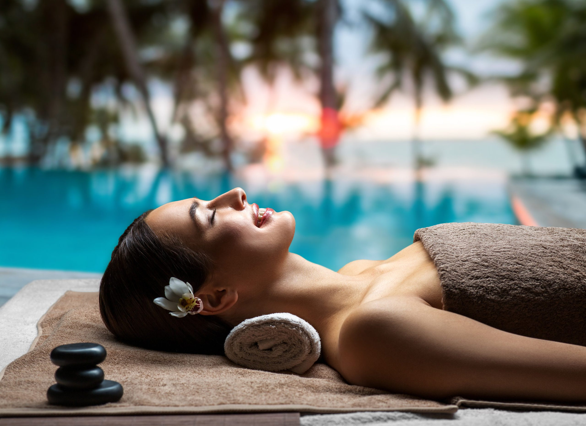 wellness, beauty and relaxation concept - young woman lying at spa over tropical beach background in french polynesia