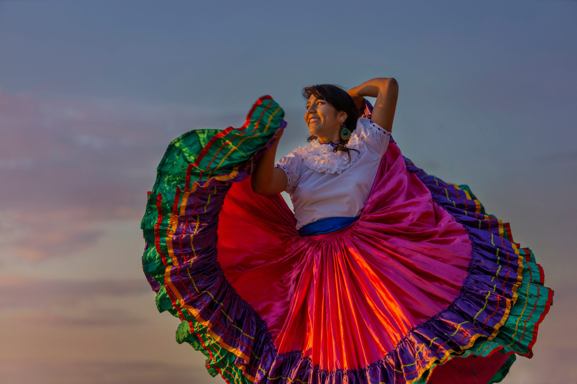 Costa Rican woman in traditional Guanacaste dress dancing in sunset light.