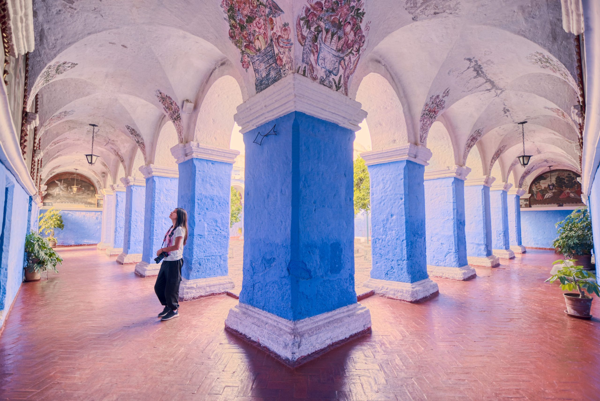 Turista latina apreciando las pinturas del claustro de los naranjos del monasterio Santa Catalina en Arequipa