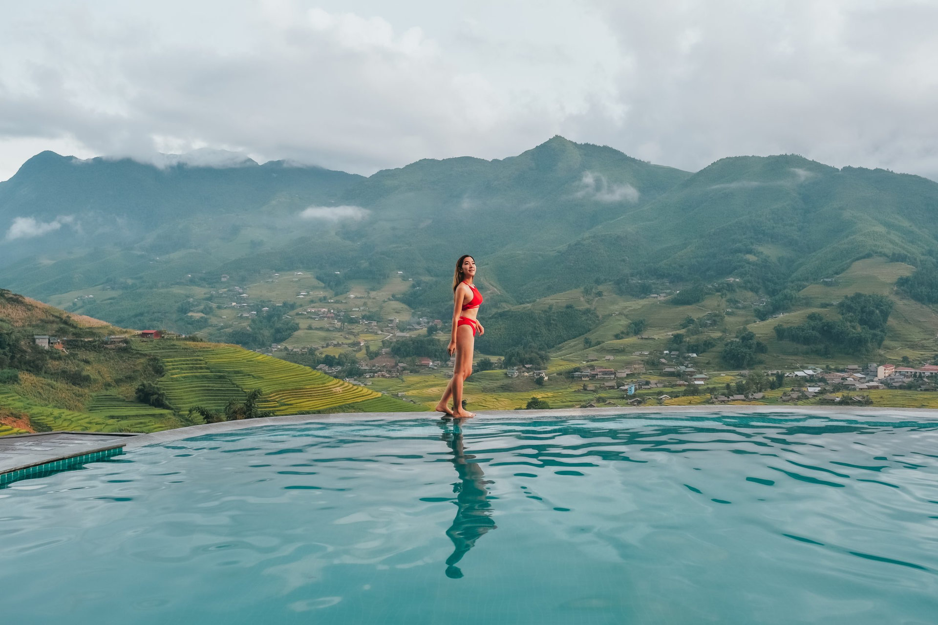 Young woman traveler relaxing at infinity pool with beautiful nature landscape mountains in Sapa, Vietnam