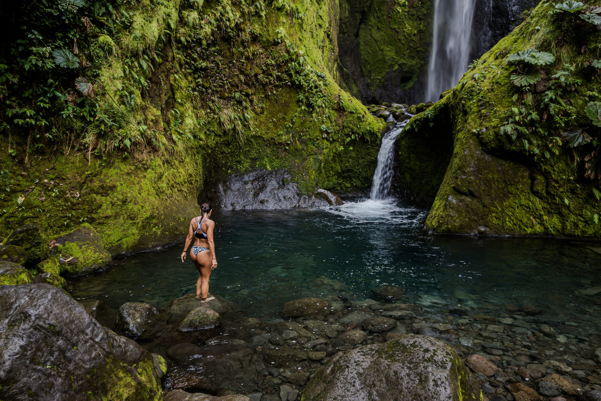 Beautiful aerial footage view of a bajos del toro waterfall in Costa Rica, with a gorgeous woman bathing