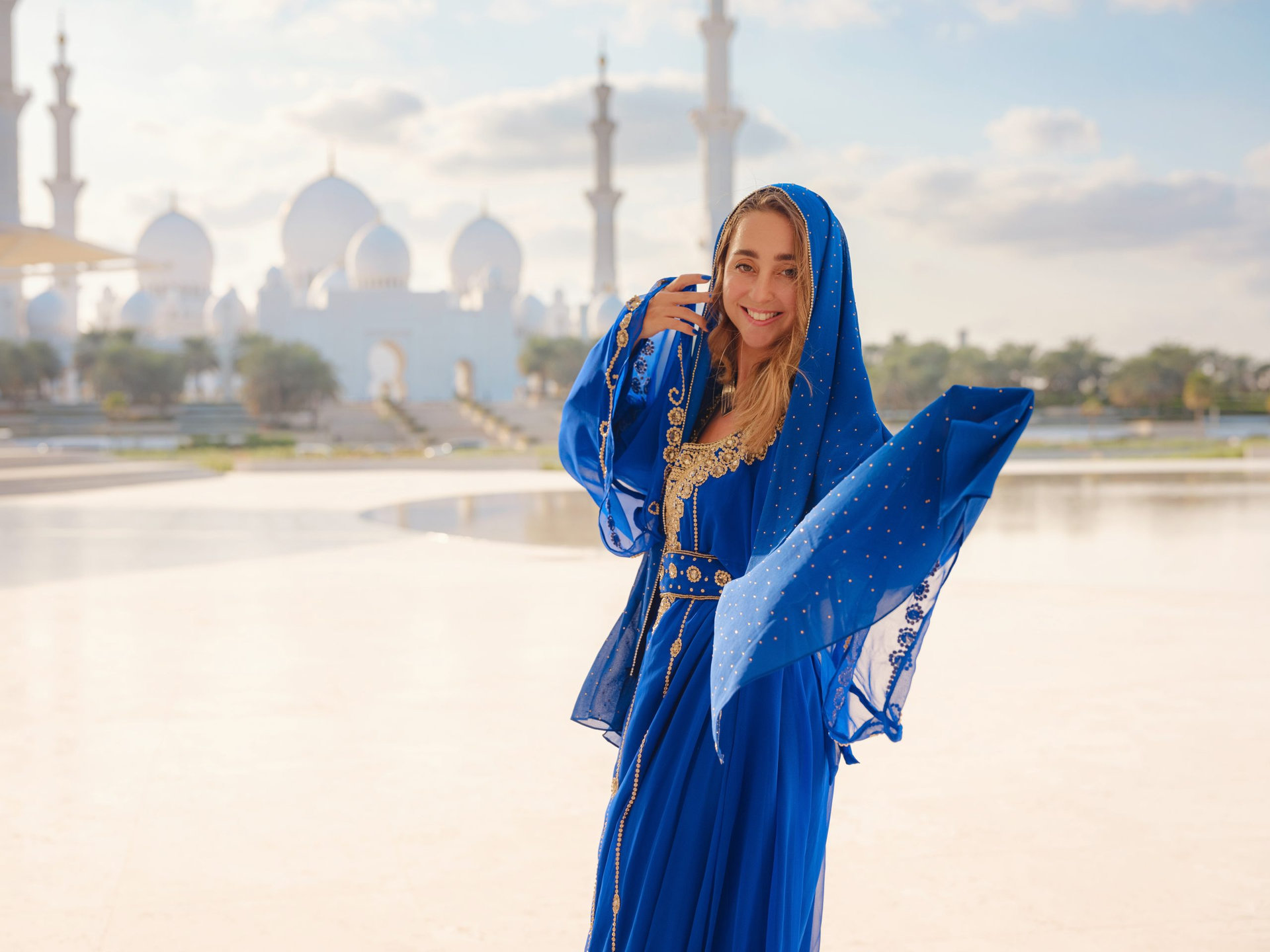 Travel to the United Arab Emirates, Abu Dhabi. Woman in blue Arabic dress near Sheikh Zayed Great white mosque. famous Abu Dhabi sightseeing.