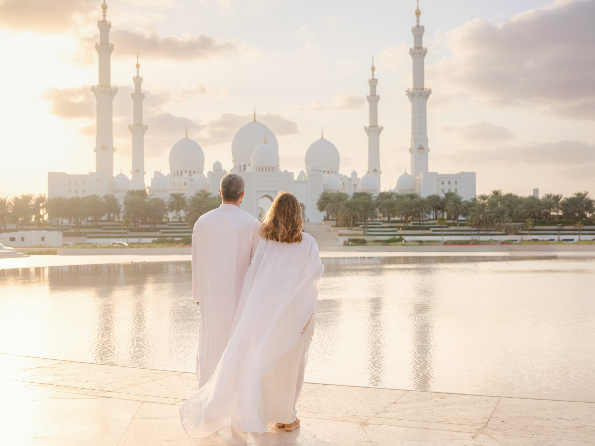 Travel to the United Arab Emirates, Abu Dhabi. Arab couple visiting park near Grand Mosque in Abu Dhabi wearing traditional dress.