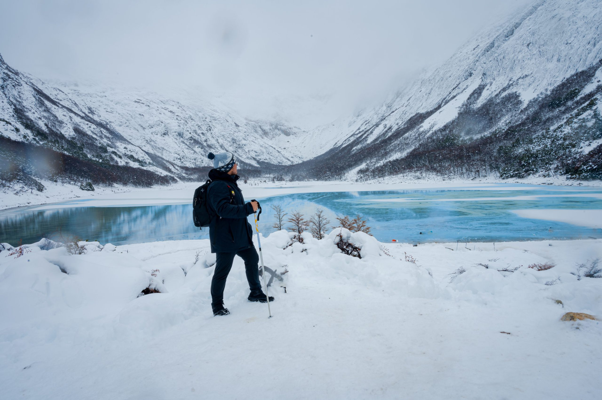 Hiker photographer in snowy mountains in ushuaia emerald lagoon