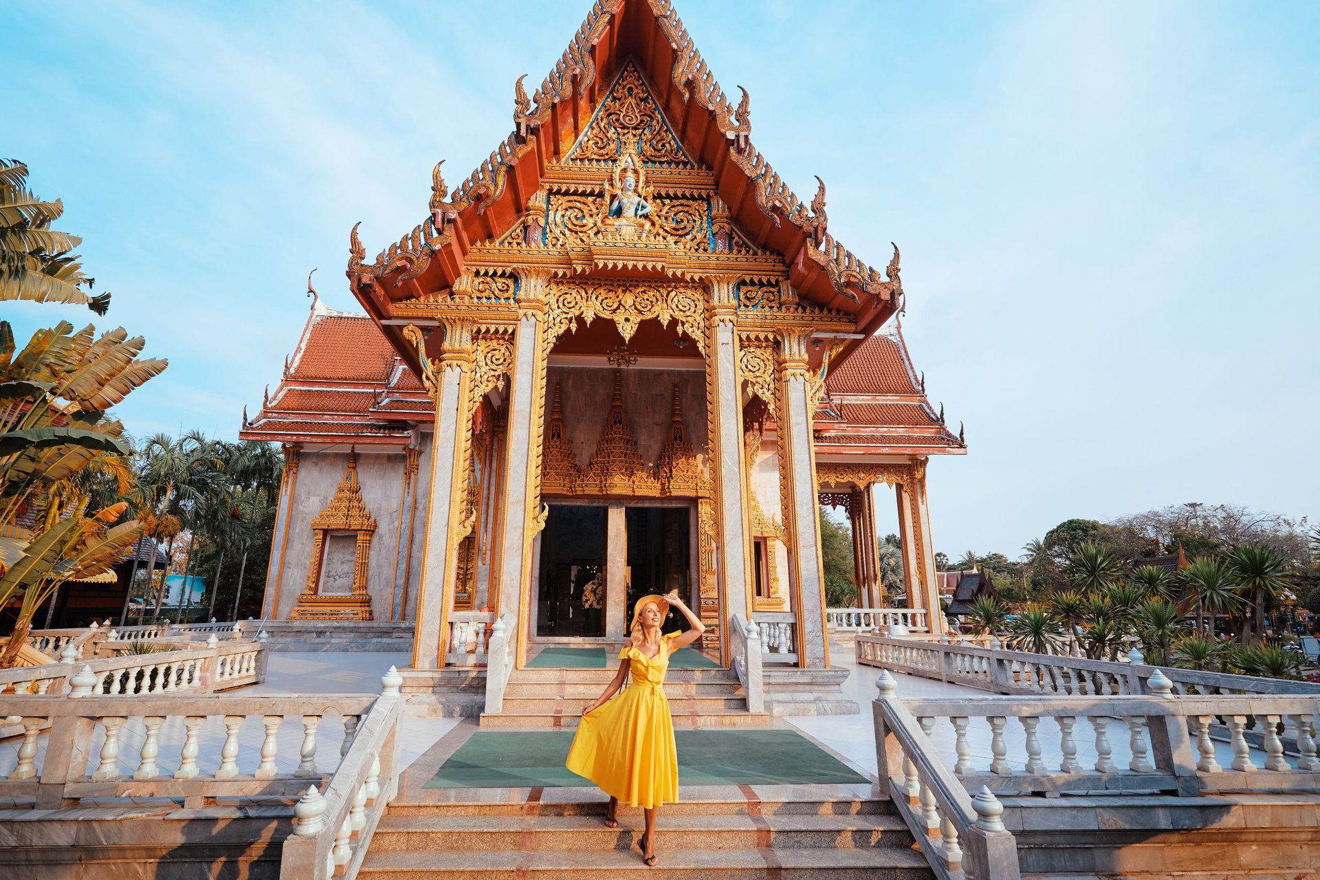 Travel by Asia . Young woman in hat and yellow dress walking near the Chalong buddhist temple on Phuket Island in Thailand.