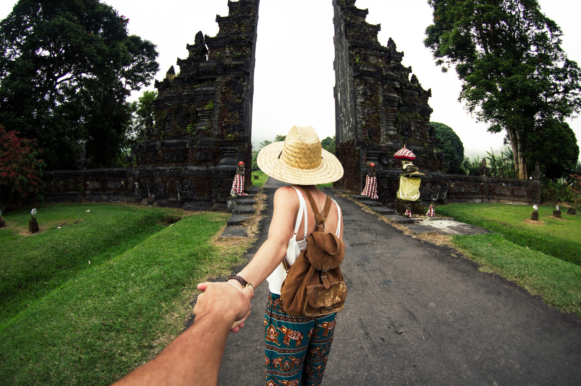 Woman in asian dress and hat holding man by hand travelling Asia
