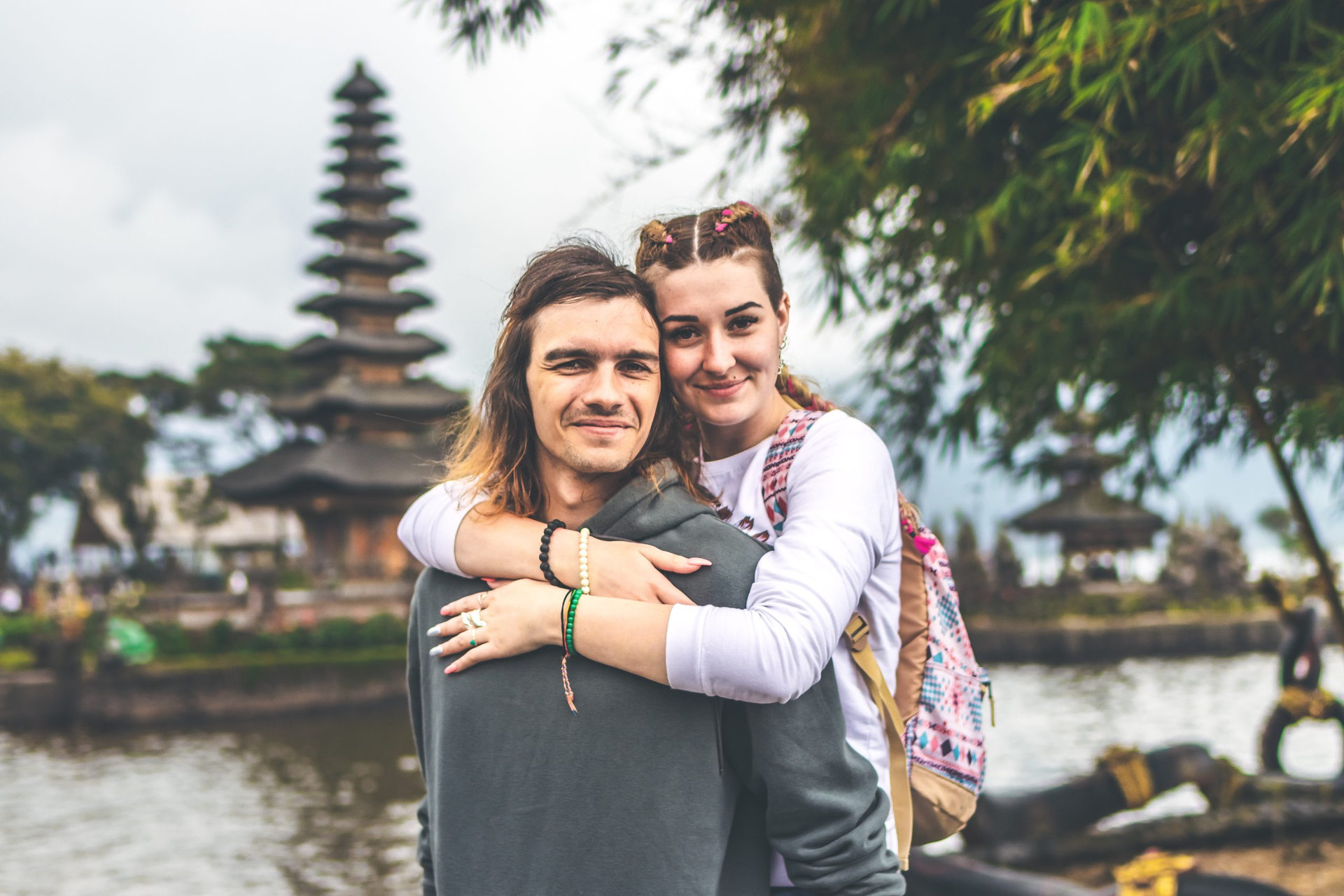 Young romantic couple of trourists on the Ulan Danu temple background. Bali island. Indonesia.